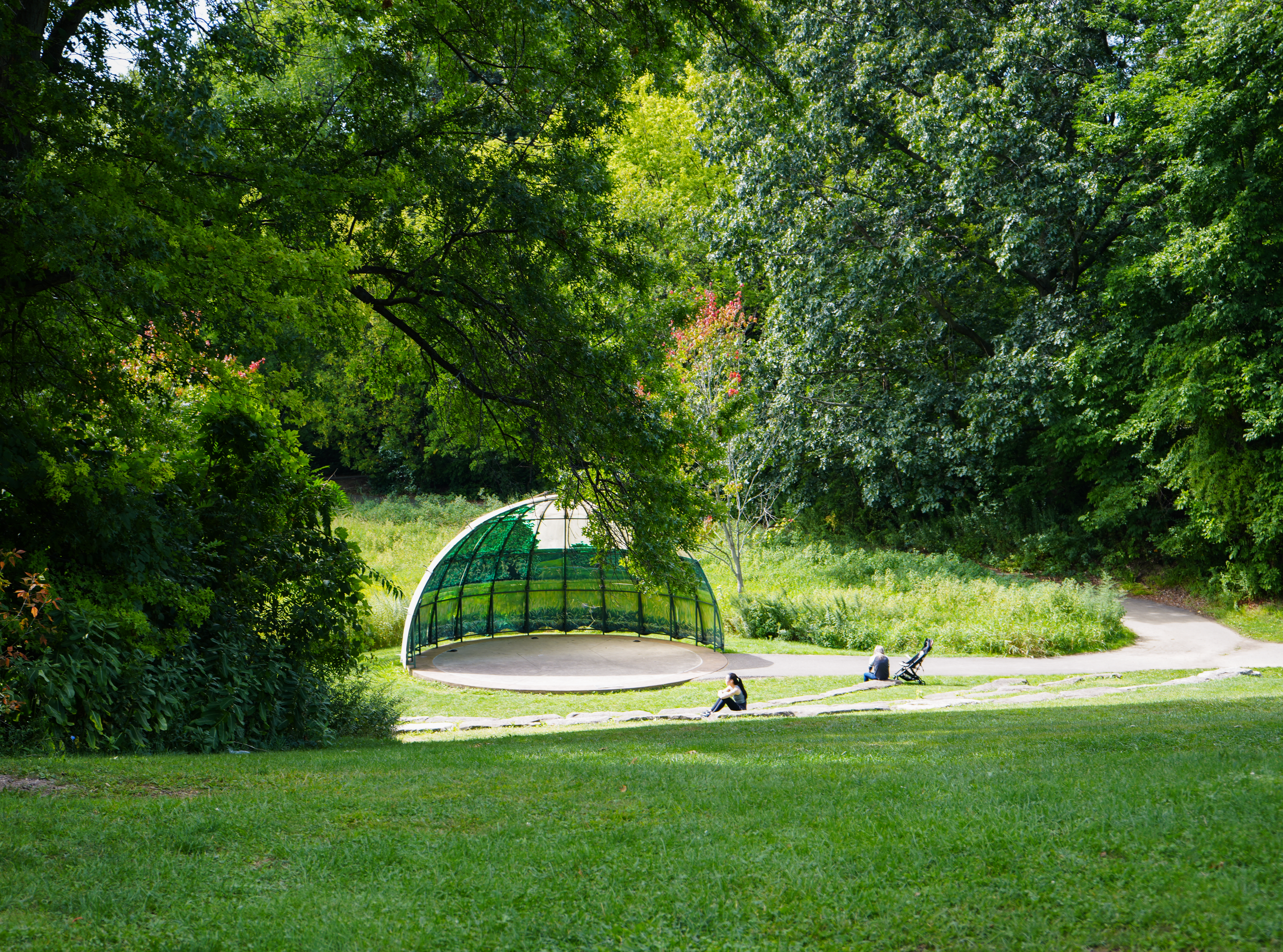 Sunlit wooden amphitheater surrounded by green trees in Frontier Park